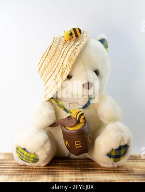 Shot of the teddy bear on a wooden base with a white plain background. Stock Photo