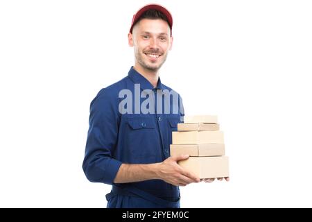 Horizontal medium portrait of handsome young adult Caucasian delivery man wearing blue uniform holding boxes, white background Stock Photo