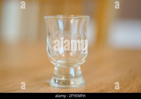 POZNAN, POLAND - Apr 01, 2016: Small empty vodka glass standing on wooden table Stock Photo