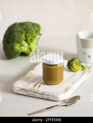 Closed glass jar with baby food broccoli smoothie on wooden board. Layout. The concept of baby food, the first feeding. Stock Photo
