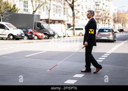 Blind Man Walking On Sidewalk Holding Stick Wearing Armband Stock Photo