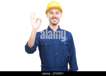 Horizontal medium portrait of modern handsome young adult Caucasian engineer wearing blue uniform showing OK sign looking at camera, white background Stock Photo
