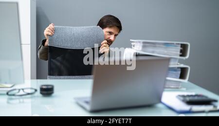 Scared Man Hiding Behind Office Desk In Room Stock Photo