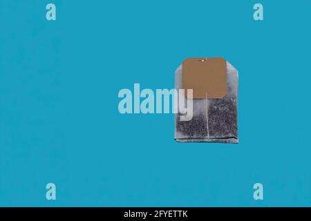 Disposable tea bag with tag. Front view from above is Isolate on blue background. Stock Photo