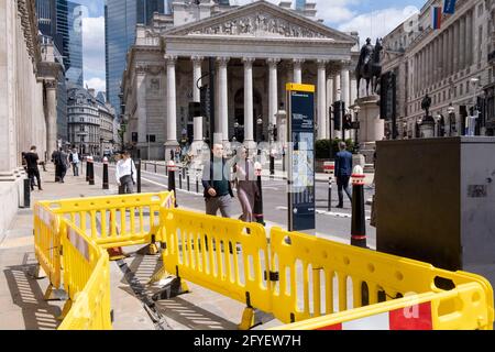 Pedestrians walk around the disruption caused by yellow roadworks barriers, set up on the pavement by street contractors 'Riney' at Bank, in the City of London, the capital's financial district, on 27th May 2021, in London, England. Stock Photo