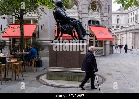 Pedestrians and lunchtime drinkers alongside the statue of Victorian philanthropist, entrepreneur and banker George Peabody (1795 to 1869), in the City of London, the capital's financial district, on 27th May 2021, in London, England. Stock Photo