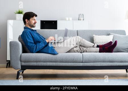 Man Using Laptop Computer In Living Room Stock Photo