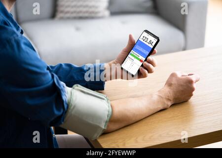 Blood Pressure Check Using Smart Monitor. African Patient Man Stock Photo