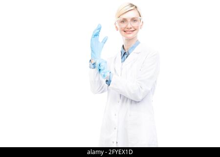 Horizontal medium portrait of successful beautiful Caucasian doctor wearing white coat putting on latex gloves, white background Stock Photo