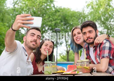 Group of happy friends taking a selfie and having fun in a park. Picnic on a sunny summer day. Stock Photo