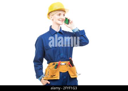 Horizontal medium portrait of modern professional female construction worker wearing blue uniform talking on phone, white background Stock Photo