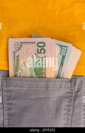 Macro shot of trendy jeans with US dollar bills in a pocket. Dollars in jeans. Financial concept. Stock Photo