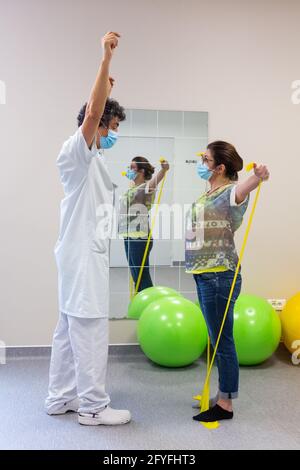 Muscle stregthening and rehabilitation session with a physiotherapist Active physiotherapy exercises with elastic bands, Here strengthening of the upp Stock Photo