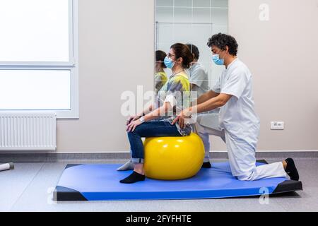 Muscle strengthening session with a physiotherapist to relieve lower back pain with a rehabilitation ball (Swiss Ball). Limoges hospital, France. Stock Photo