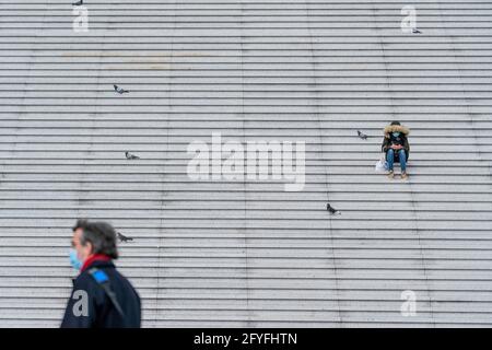 Person sitting alone on stairs during pandemia. Stock Photo