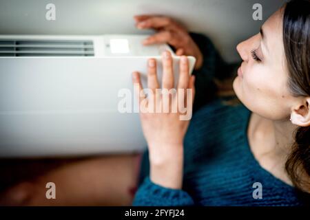 Woman adjusting a thermostatic radiator valve on a domestic radiator. Stock Photo