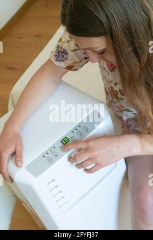 Woman using an air conditioner. Stock Photo