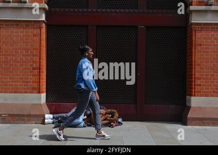 London (UK), 27 May 2021: A (homeless) couple sleep entwined on the streets outside St Pancras International rail Station. Stock Photo