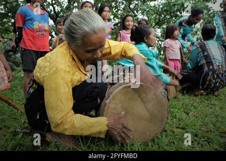 A woman playing percussive instrument as the musical background for a show of 'caci' (Flores Island's traditional whip fight, martial art) in Liang Ndara village, Mbeliling, West Manggarai, Flores, East Nusa Tenggara, Indonesia. Stock Photo