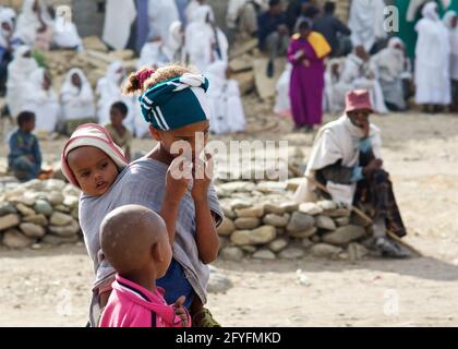 Ethiopian little girl, wearing headscarf, carrying a baby and attending the True Cross ceremony at Wukro village, Tigray, Ethiopia Stock Photo
