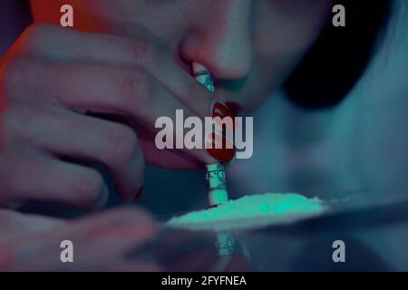 Portrait of a girl sniffing a line of white drug cocaine powder. Addict and addiction concept. Stock Photo