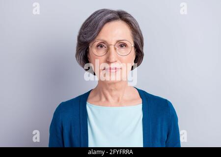 Portrait of attractive content intellectual gray haired woman wearing specs isolated over grey pastel color background Stock Photo