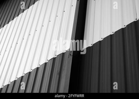 Details of black and white corrugated iron sheet used as a facade of a warehouse or factory. Texture of a seamless corrugated zinc sheet metal Stock Photo