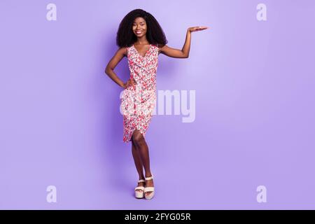 Full size photo of nice optimistic curly brown hairdo lady show high wear colorful dress isolated on violet background Stock Photo