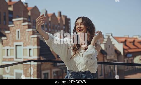 happy young woman taking selfie near blurred buildings Stock Photo