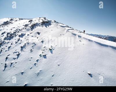 Aerial drone shot of the small man hiking at winter mountain landscape in Almaty, Kazakhstan. Stock Photo