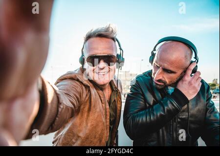 Disc jockeys having fun doing selfie while playing music for tourist people at club party outdoor - Live event, music and fun concept - Entertainment Stock Photo