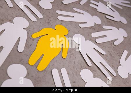Yellow silhouette of fat human in center on brown background. White figures of people around. Stock Photo