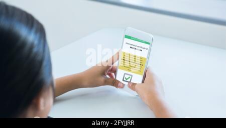 Composition of woman holding smartphone with covid 19 international certificate of vaccination Stock Photo