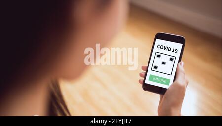 Composition of woman holding smartphone with covid 19 immune text Stock Photo