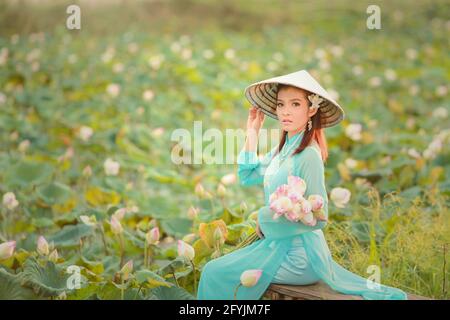 Portrait of a beautiful woman in a traditional conical hat holding a bunch of water lily flowers, Thailand Stock Photo