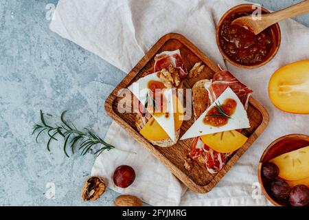 Overhead view of two slices of toast with serrano ham, cheese, persimmon and chutney Stock Photo