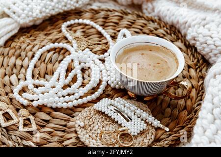 Cup of coffee with rings, earrings, necklaces and hair clips Stock Photo