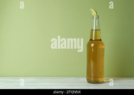 Bottle of beer with lime slice against green background Stock Photo