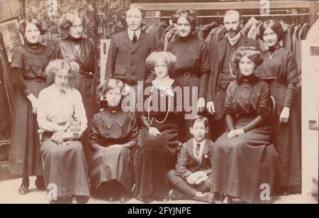 Vintage early 20th century photographic postcard showing male and female staff from a clothing shop. Stock Photo