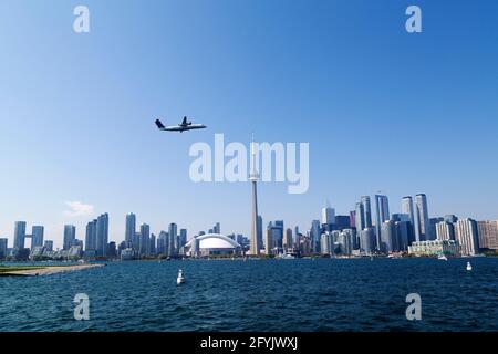 An aircraft takes off from Billy Bishop Toronto City Airport n Toronto, Ontario, Canada. The Toronto cityscape can be seen beyong the waterfront. Stock Photo
