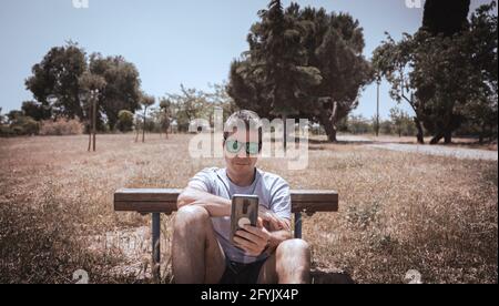 a man in a park looking at his mobile doing exercises Stock Photo