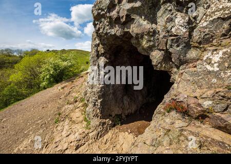 The entrance to Clutter’s Cave in the Malvern Hills with British Camp in the background, Worcestershire, England Stock Photo