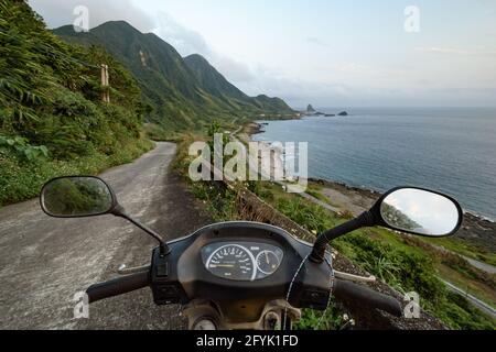 View of the island of Lanyu rugged coast over motorcycle handlebars. Taiwan's offshore islands travelling. Stock Photo