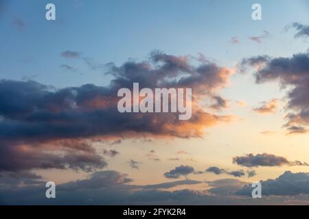 The try of two clouds to join against the wind concept. Sunbeams through heavy dark colorful cloudy sky background, space. Dramatic abstract scene wit Stock Photo