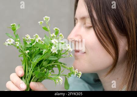 Beautiful young woman sniffing wild flowers. A bouquet of flowers in female hands. Spring and spring mood Stock Photo