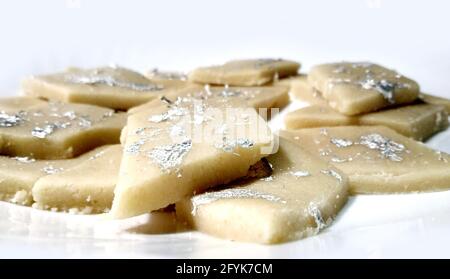 Kaju Katli is a Diamond shape Indian sweet made using cashew sugar and mava, served in a plate isolated on white background. selective focus Stock Photo