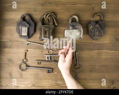 Hand holding a magnifying glass over a keyhole Stock Photo