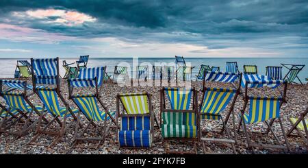 Deck chairs on the pebble beach at Beer in Devon on a summer evening. Stock Photo