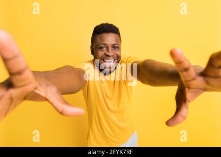 Joyful excited Afro American in trendy yellow T-shirt exclaiming emotionally and gesturing actively with both hands in front , amazed with good news Stock Photo