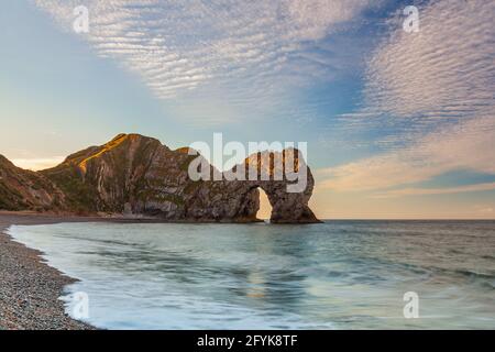 Sunrise at the wonderful Durdle Door in Dorset, with a mackerel sky. Stock Photo